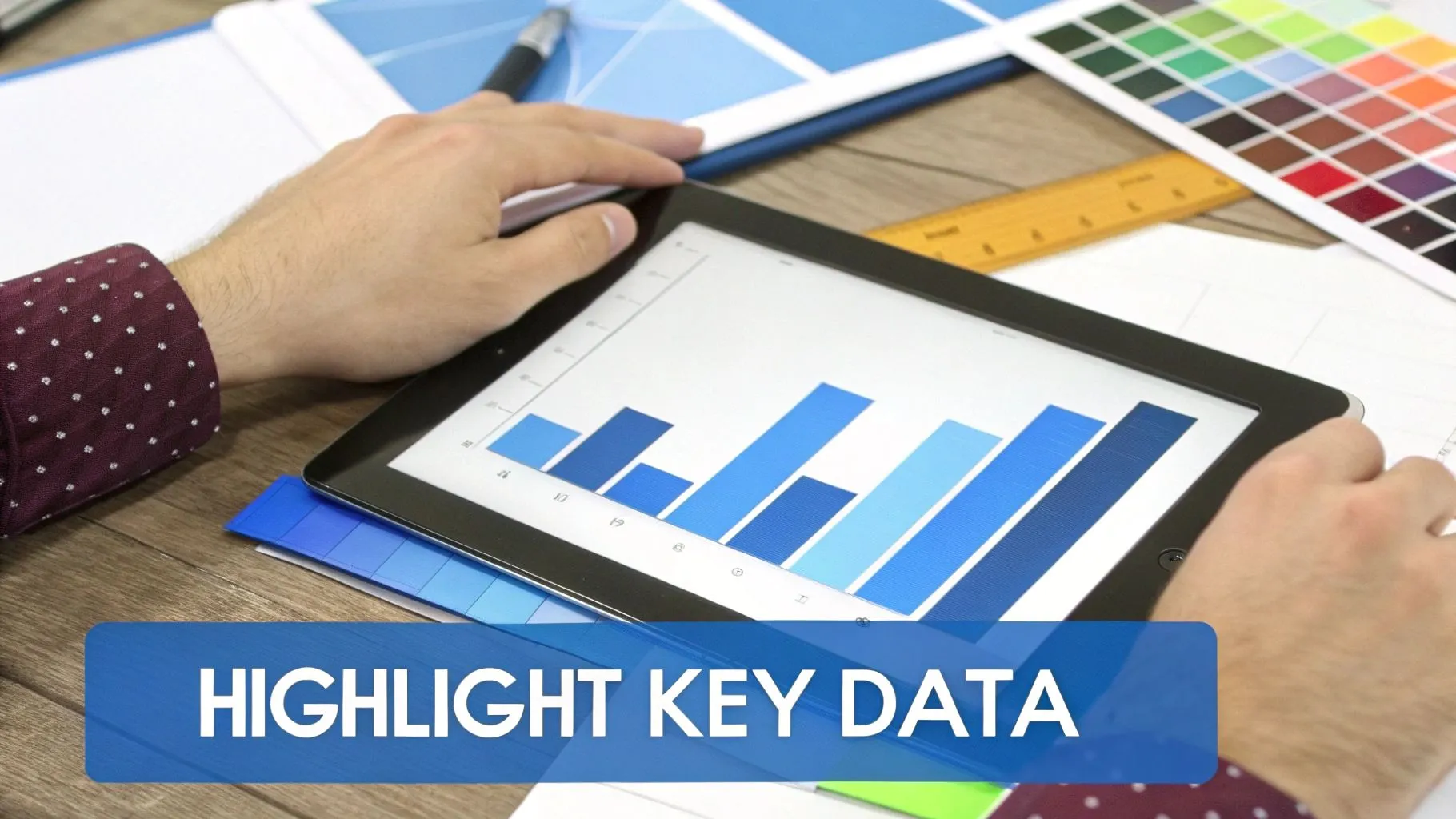 Hands interact with a tablet displaying a blue bar chart for data analysis and visualization.