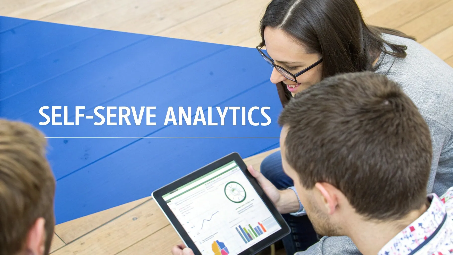 Three people view a tablet with self-serve analytics dashboards, showcasing data insights and collaboration.